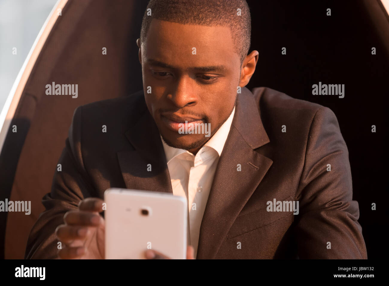 Portrait of attractive african american businessman holding tablet, assis sur une chaise, l'organisation de la planification de réunions, en utilisant les applications d'entreprise, banque en ligne Banque D'Images