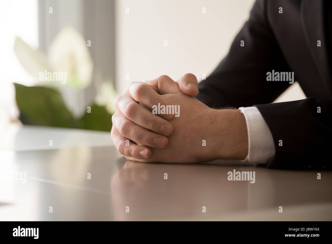 Close up of male serra les mains jointes ensemble à la table, la préparation des affaires, en se concentrant d'entrevue d'emploi avant d'importantes négociations, pensez Banque D'Images