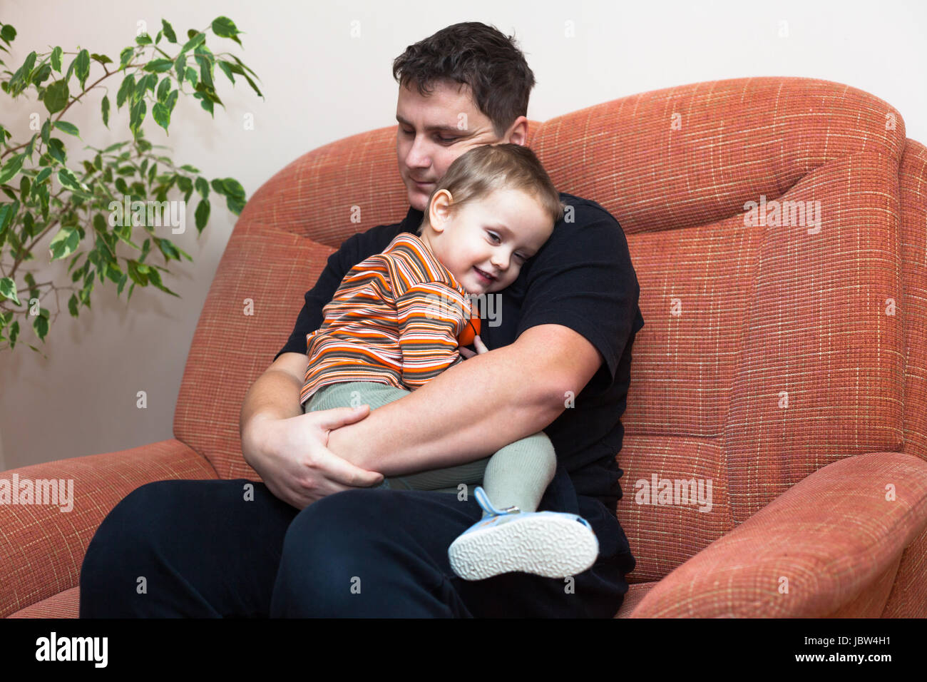 Happy father hugging son enfant, assis sur le canapé à la maison Banque D'Images