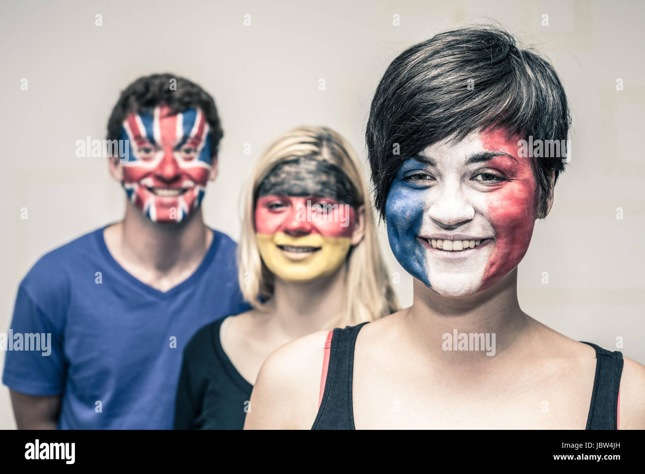 Groupe de gens heureux avec drapeaux peints sur leurs visages. Banque D'Images