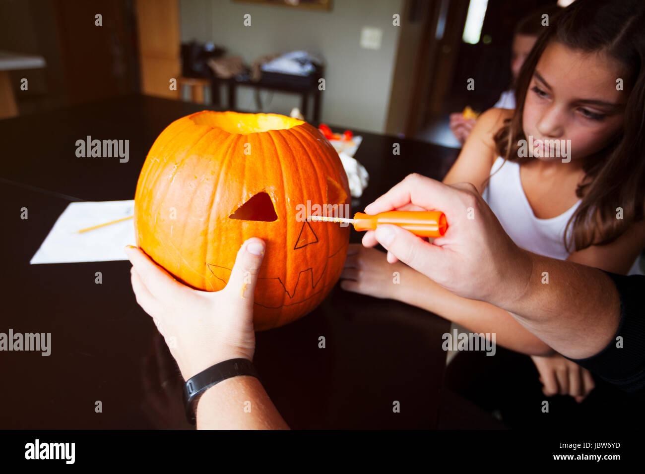 Fille regardant père carve pumpkin Banque D'Images