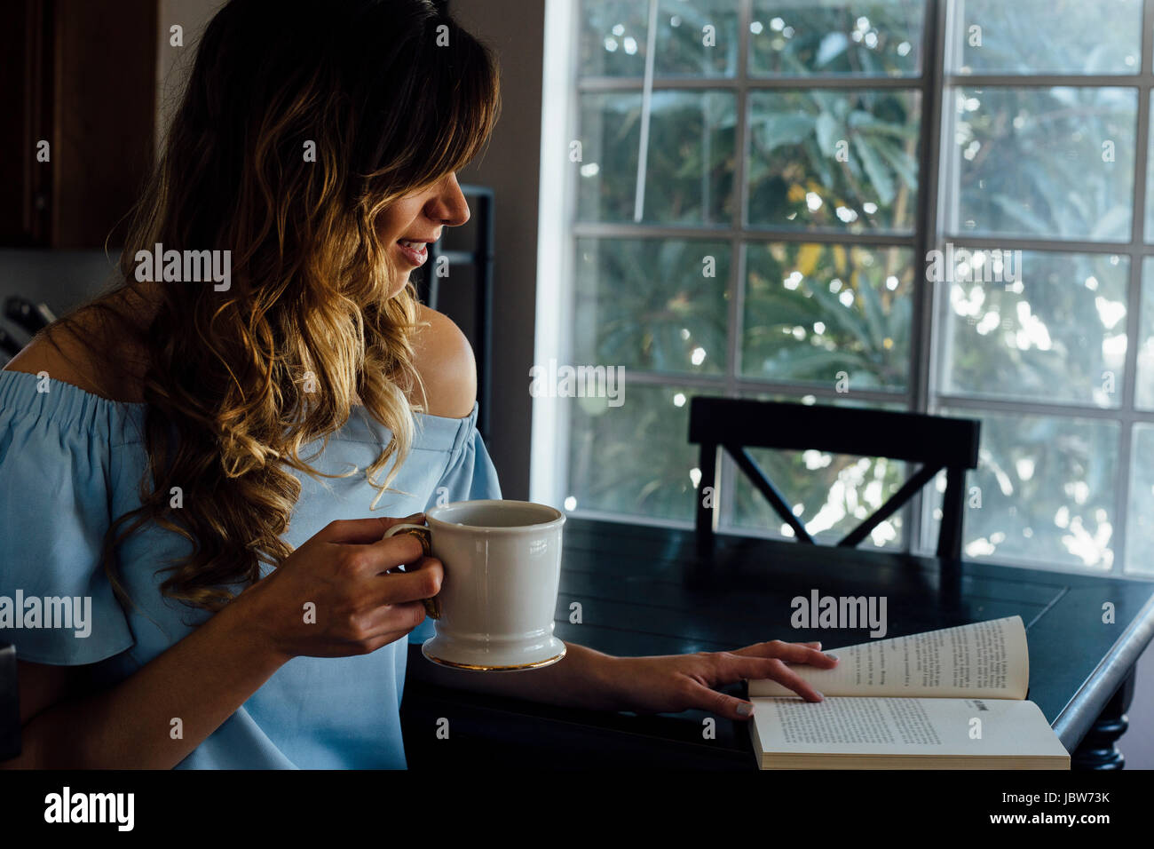 Young woman reading book at table Banque D'Images