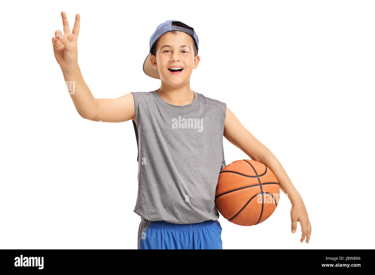 Heureux enfant avec un basket-ball faisant un signe de victoire isolé sur fond blanc Banque D'Images
