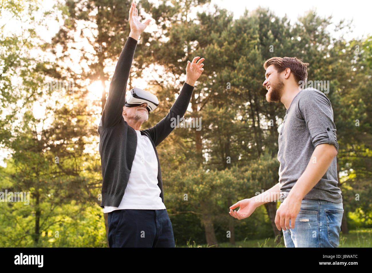 Jeune homme et son père senior avec lunettes VR à l'extérieur. Banque D'Images