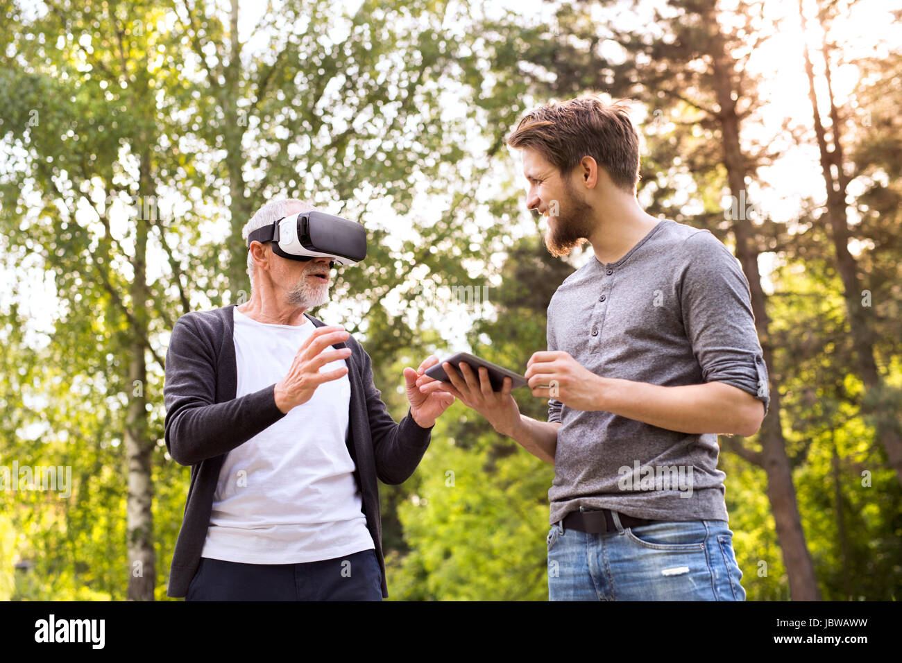 Jeune homme et son père senior avec lunettes VR à l'extérieur. Banque D'Images