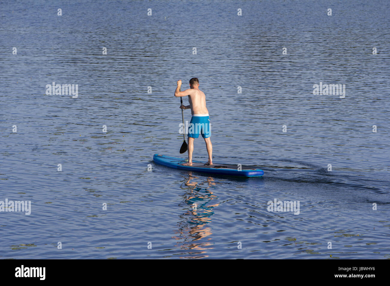 Man on Paddle Board paddling out au lac Banque D'Images