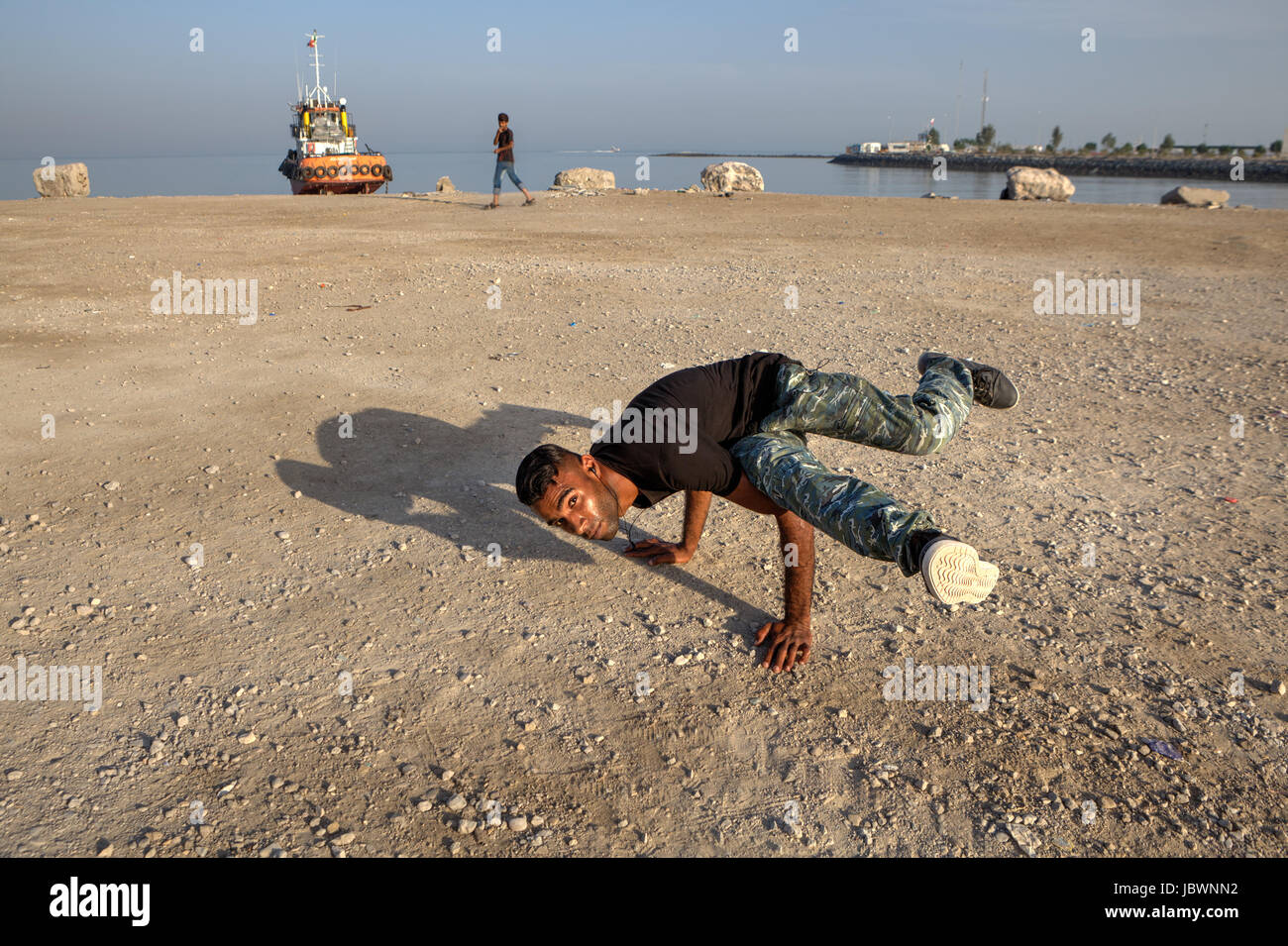 Bandar Abbas, Iran, Province Hormozgan - 16 avril, 2017 : Le jeune homme iranien montre une figure, un breakdance sur la plage du golfe Persique. Banque D'Images