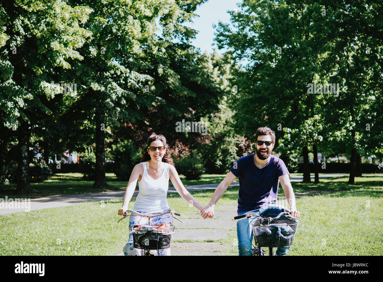 Couple holding hands en faisant du vélo dans le parc, Arezzo, Toscane, Italie Banque D'Images