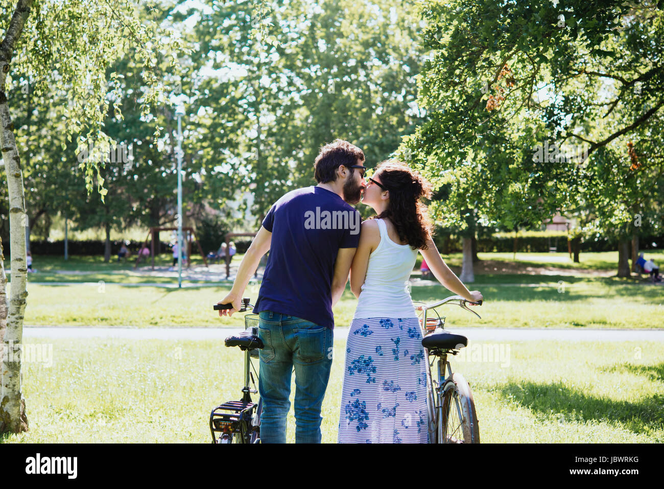 Vue arrière du couple with bicycles kissing in park, Arezzo, Toscane, Italie Banque D'Images