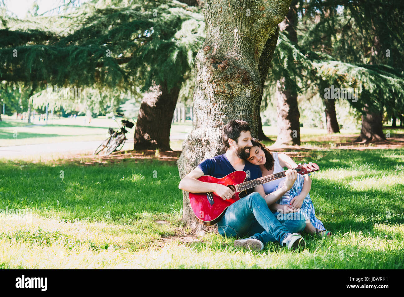 Couple assis dans un parc à jouer de la guitare, Arezzo, Toscane, Italie Banque D'Images