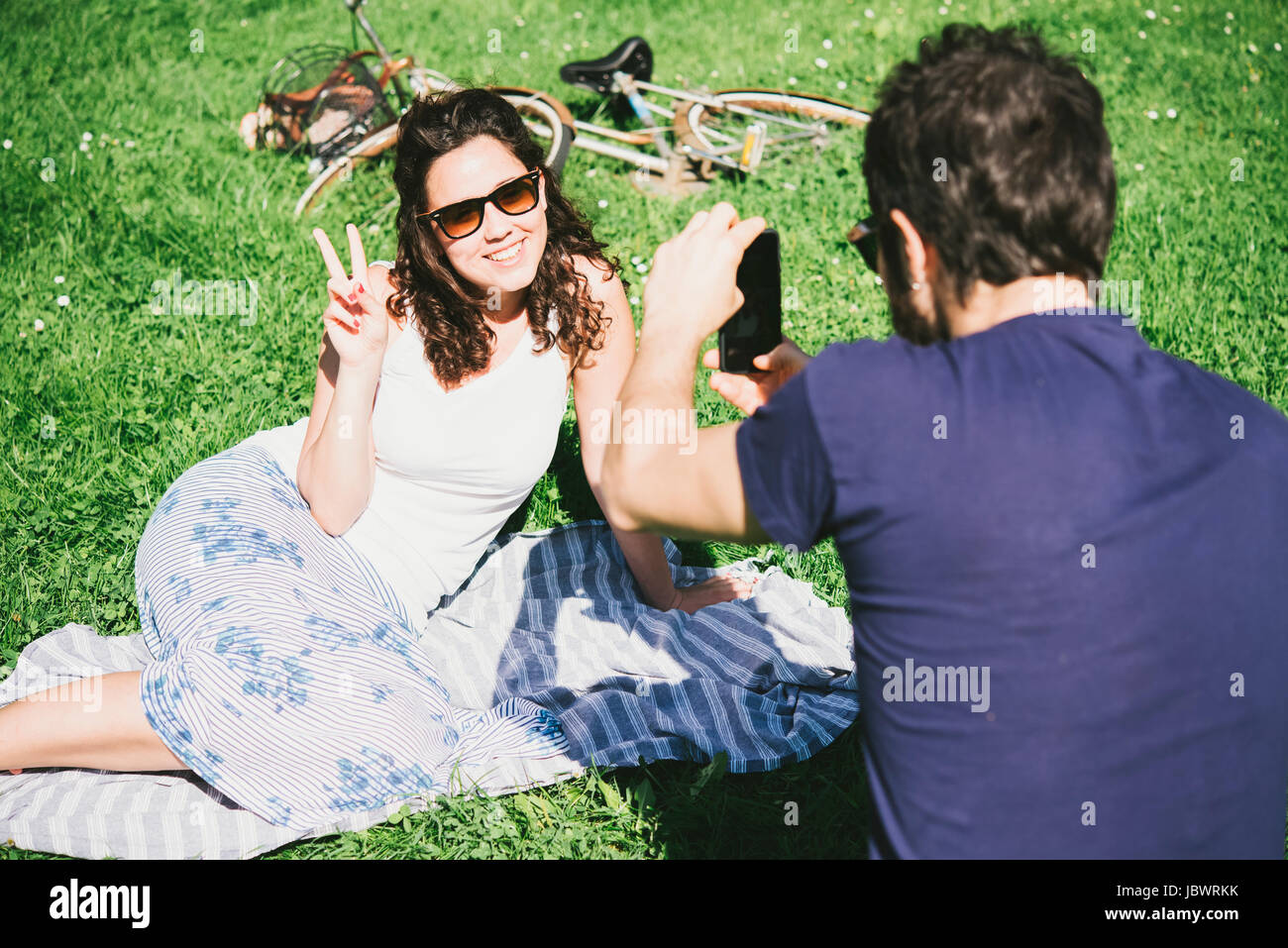 Plus d'épaule de l'homme photographie copine assis dans un parc, Arezzo, Toscane, Italie Banque D'Images