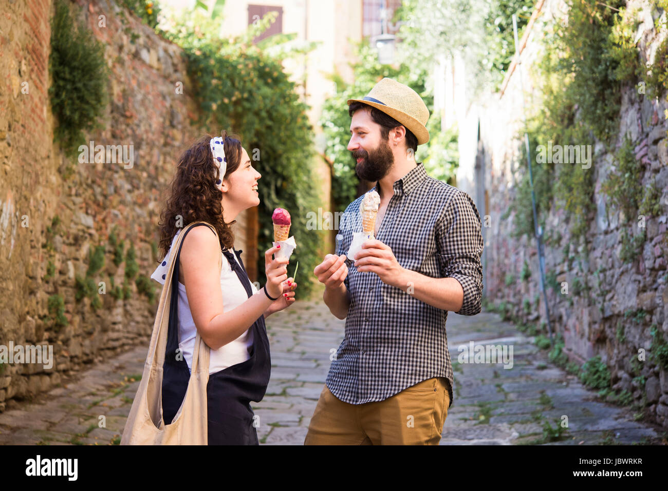 Couple avec ice cream cones sur rue pavée, Arezzo, Toscane, Italie Banque D'Images