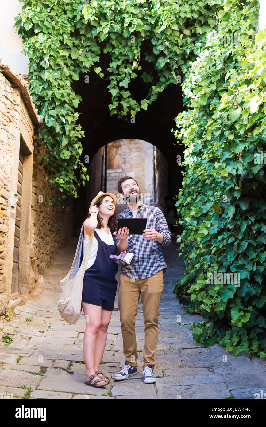 Couple avec tablette numérique à la recherche jusqu'à partir de la rue pavée, Arezzo, Toscane, Italie Banque D'Images