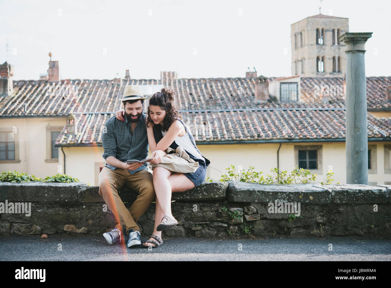 Couple sitting on wall looking at guidebook, Arezzo, Toscane, Italie Banque D'Images