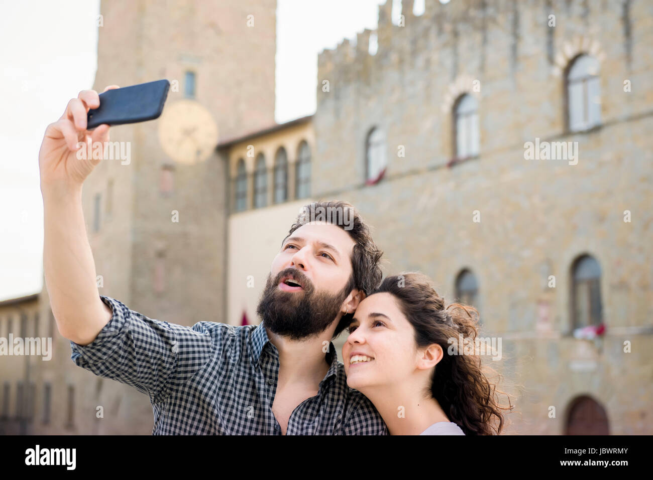Couple qui selfies smartphone par la Cathédrale d'Arezzo, Arezzo, Toscane, Italie Banque D'Images