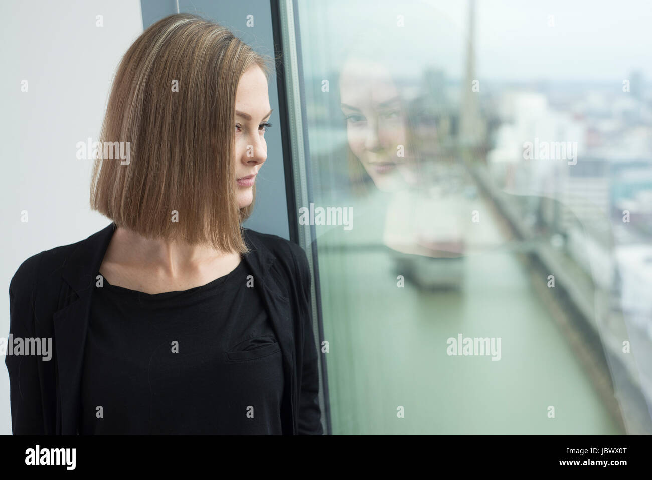 Young businesswoman looking through office window Banque D'Images