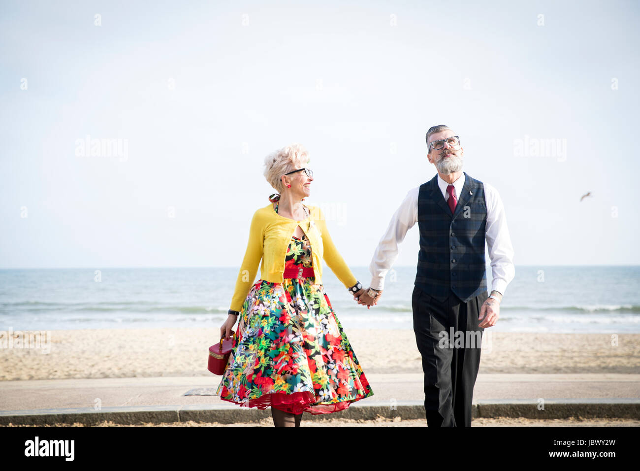 Style années 50 vintage couple holding hands and strolling on beach Banque D'Images