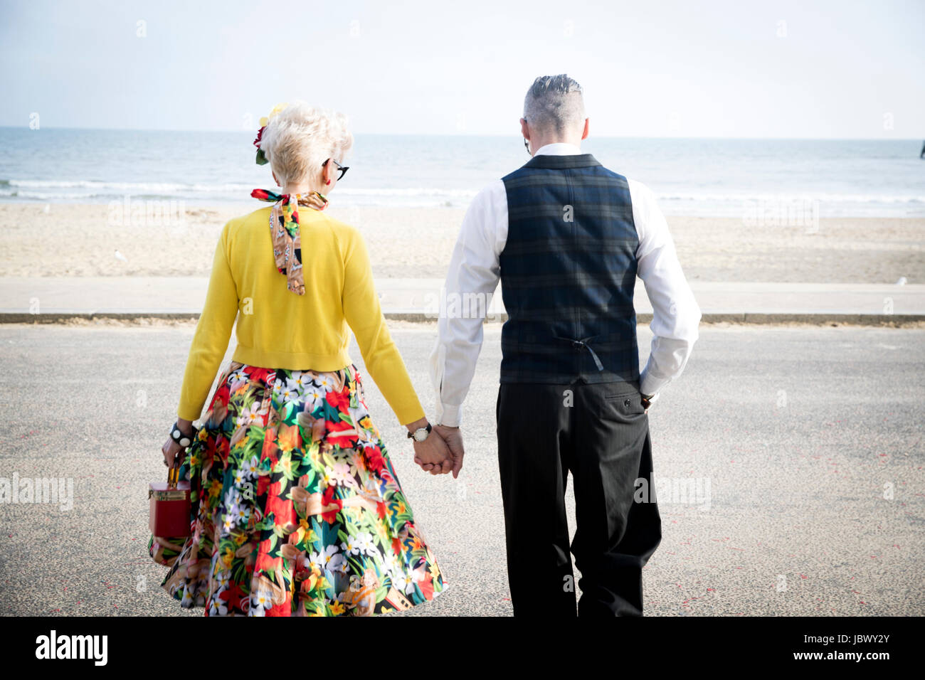 Vue arrière du style années 50 vintage couple holding hands and strolling on beach Banque D'Images