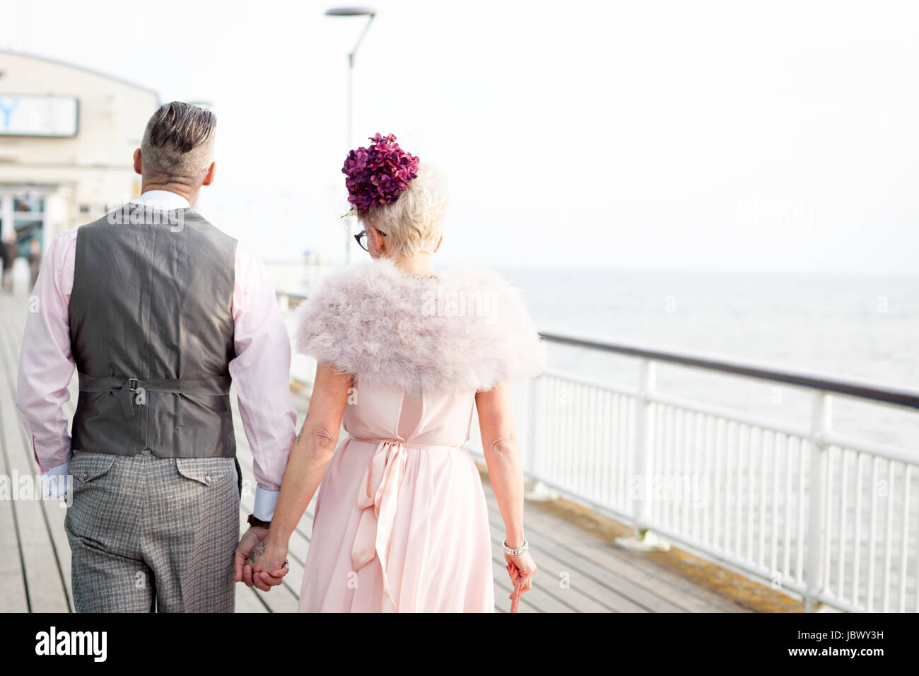 Vue arrière du style années 50 vintage couple strolling main dans la main on pier Banque D'Images