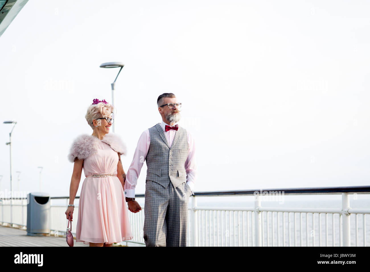Style années 50 vintage couple strolling main dans la main on pier Banque D'Images