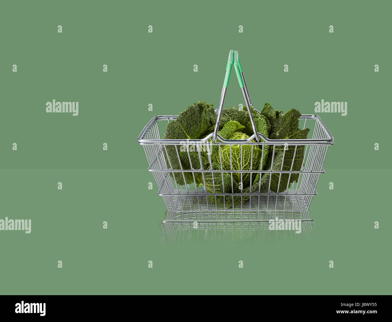 Le chou vert en miniature panier sur fond vert Banque D'Images