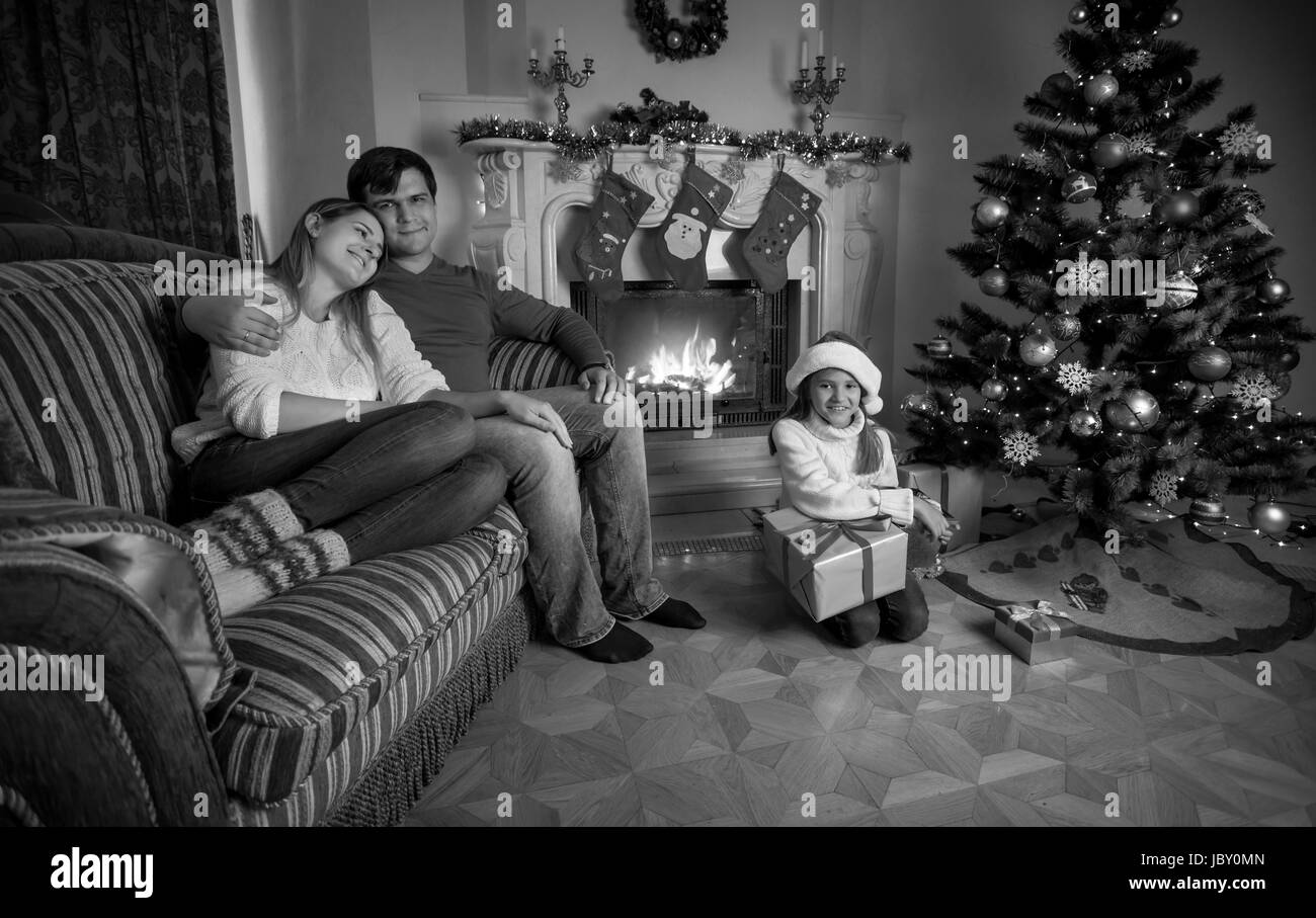 Image en noir et blanc de happy family près de cheminée à Noël Banque D'Images