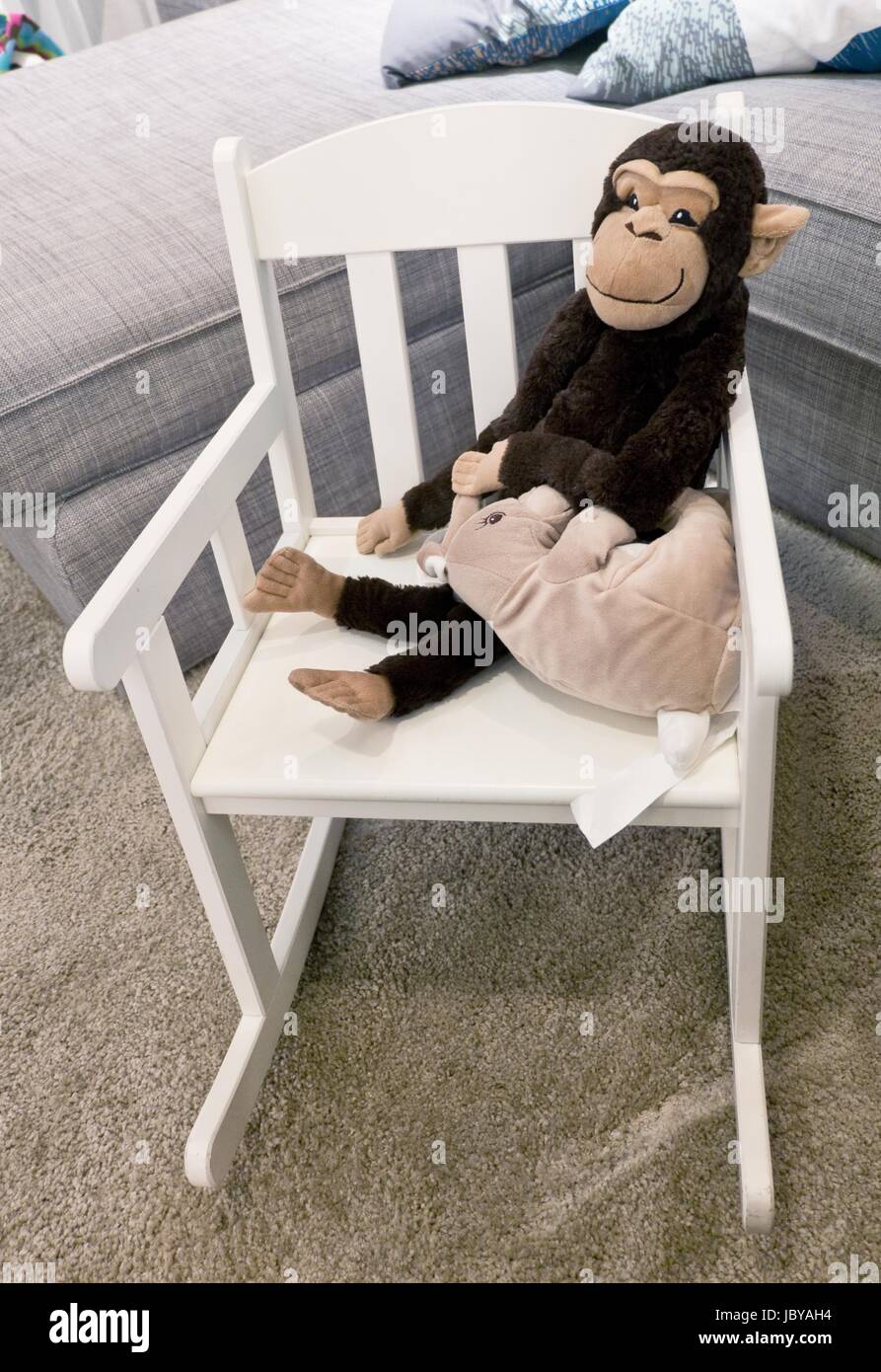 Monkey doll and toy en attente de la souris sur un petit fauteuil à bascule blanc moderne. Banque D'Images