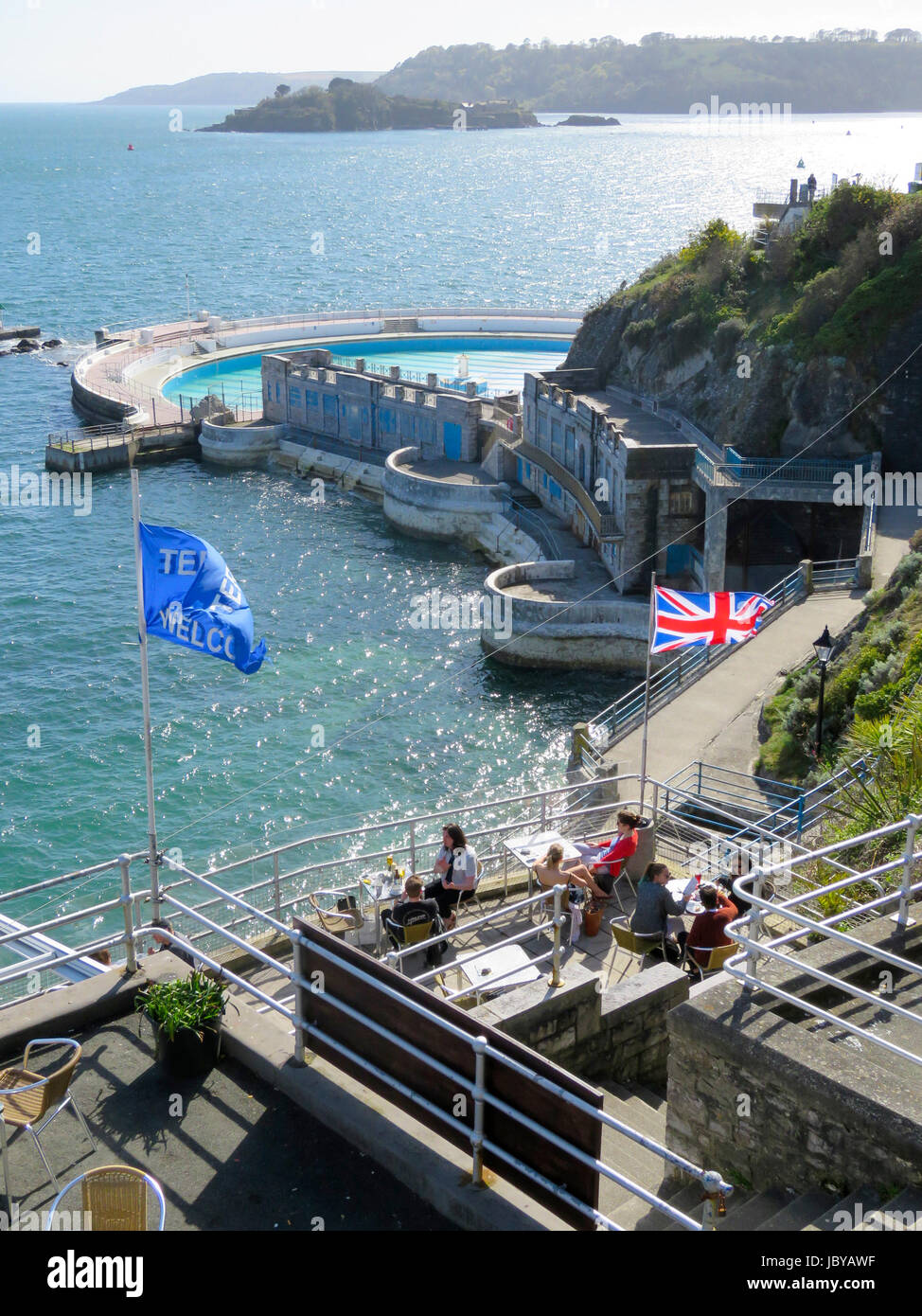 Les gens assis en terrasse de café sur Plymouth Hoe prendre des rafraîchissements aux beaux jours d'été à côté de la piscine. Tinside Soleil de scintillement de l'eau de mer bleu clair Banque D'Images