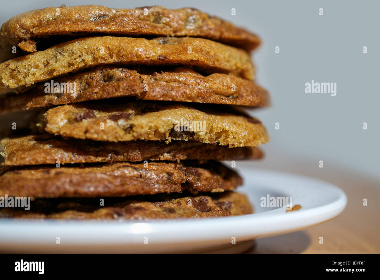 Gros plan sur pile de cookies aux pépites de chocolat en plaque blanche sur table en bois Banque D'Images