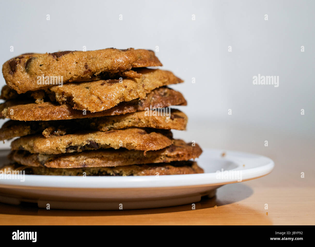 Gros plan sur pile de cookies aux pépites de chocolat en plaque blanche sur table en bois Banque D'Images