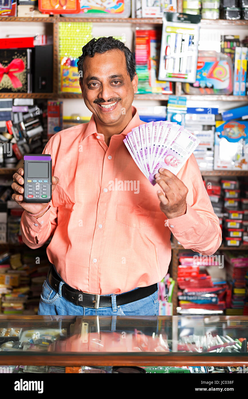1 Indian shop keeper man showing argent roupies avec lecteur de carte de crédit en magasin stationnaire Banque D'Images