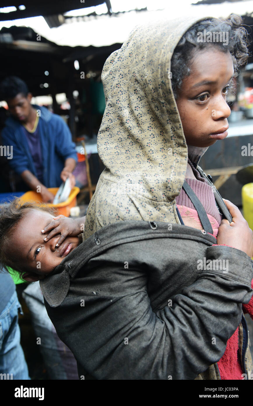 Une jeune fille portant son bébé frère pour que la mendicité pour l'argent. Banque D'Images