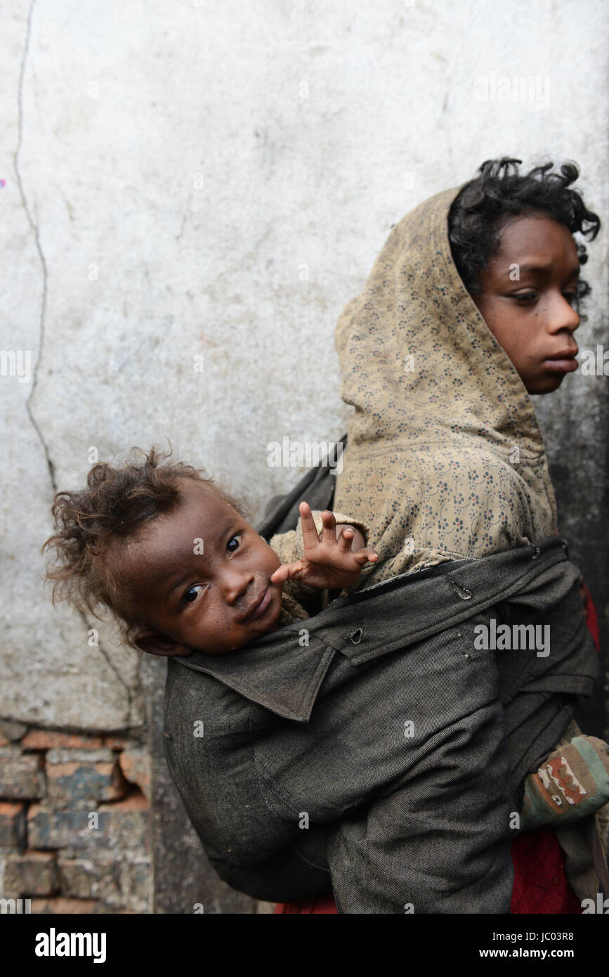 Une jeune fille portant son bébé frère pour que la mendicité pour l'argent. Banque D'Images