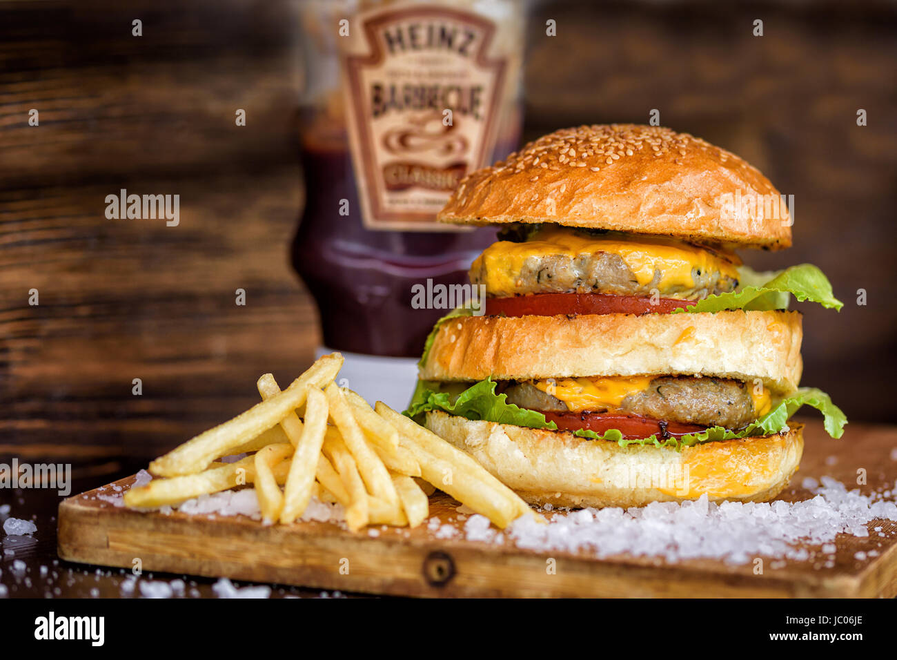 Maxi Burger fait maison avec pavé de boeuf grillé, salade, fromage, tomate, oignons, sauce barbecue, moutarde au miel, cornichons frites Banque D'Images