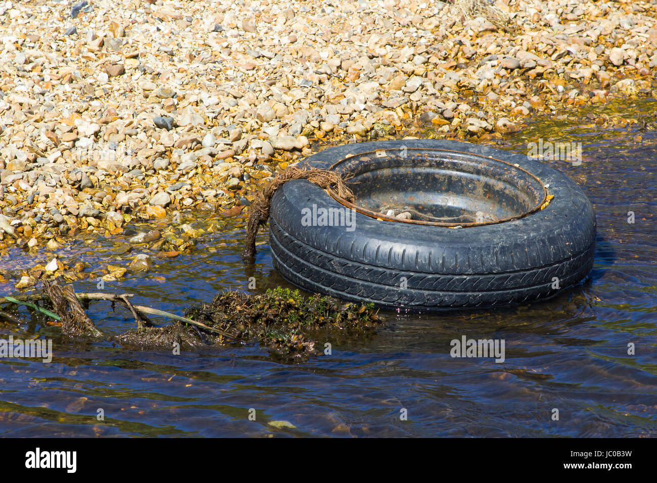 Un pneu et jante désaffectée d'un petit cours d'eau polluantes sur le Solent Way Beach sur l'eau près de Southampton dans le Hampshire Titchfield Banque D'Images