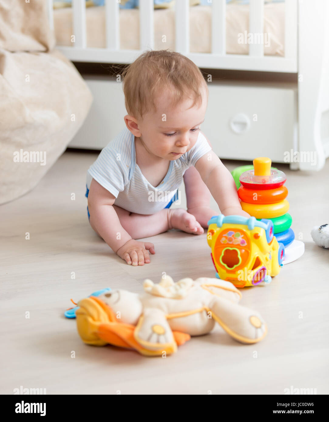 Cute 9 mois Bébé Garçon jouant avec des jouets colorés sur parole à salle  de séjour Photo Stock - Alamy