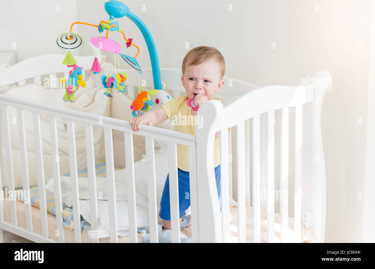 Triste à l'âge de 10 mois bébé garçon pleurant et tenant sur le côté de lit- bébé Photo Stock - Alamy