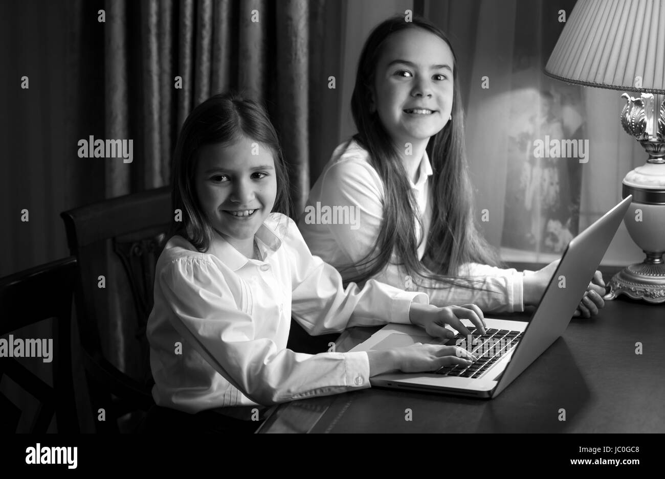 Portrait noir et blanc de deux petites sœurs using laptop Banque D'Images