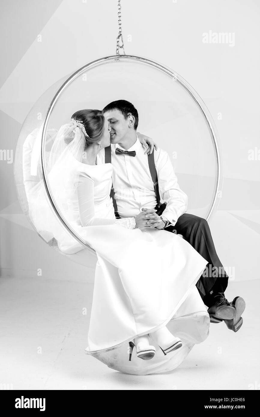 Photo en noir et blanc du couple nouvellement marié, baiser sur swing au studio Banque D'Images