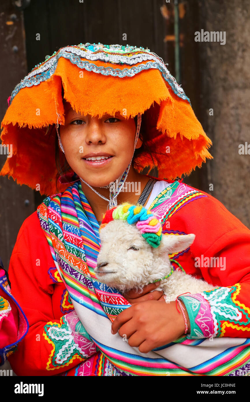 Jeune femme en costume traditionnel holding lamb dans les rues de Cusco, Pérou. En 1983 Cusco a été déclaré site du patrimoine mondial par l'UNESCO Banque D'Images