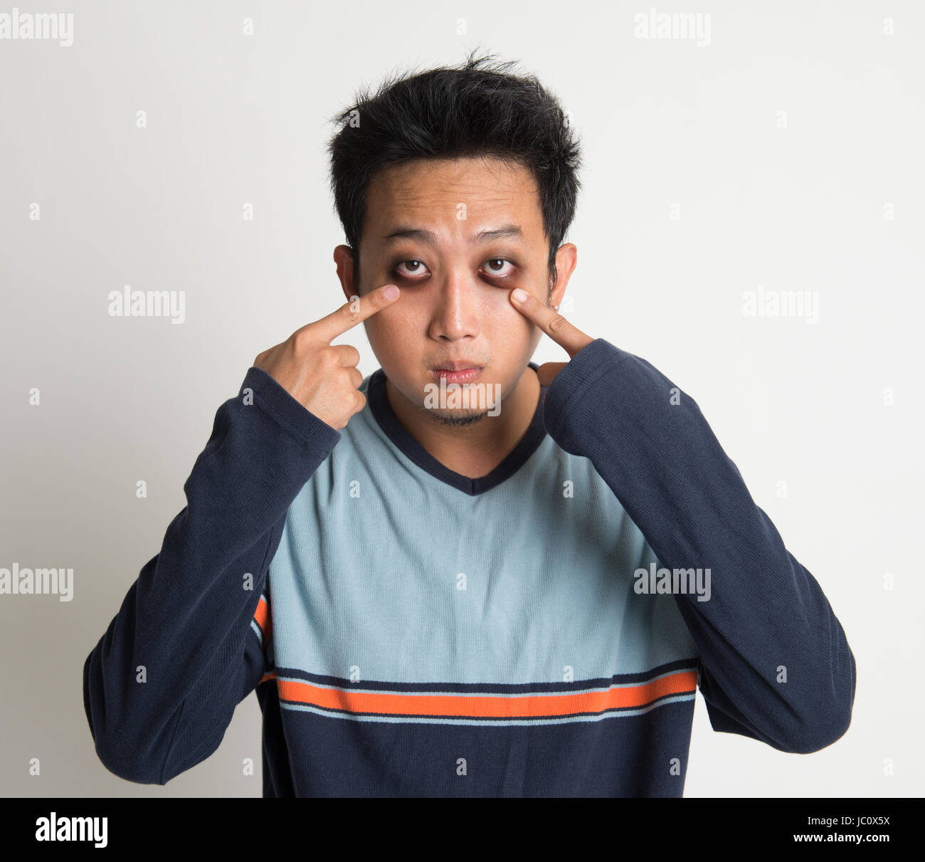 L'homme asiatique de l'insomnie, avec de grands yeux sac, sur fond uni Banque D'Images