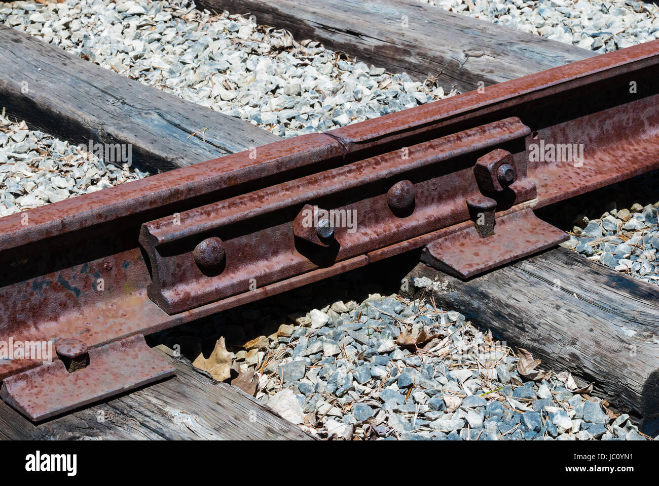 Vue oblique de traverses de chemin de fer rouillé lié avec quatre vis. Banque D'Images