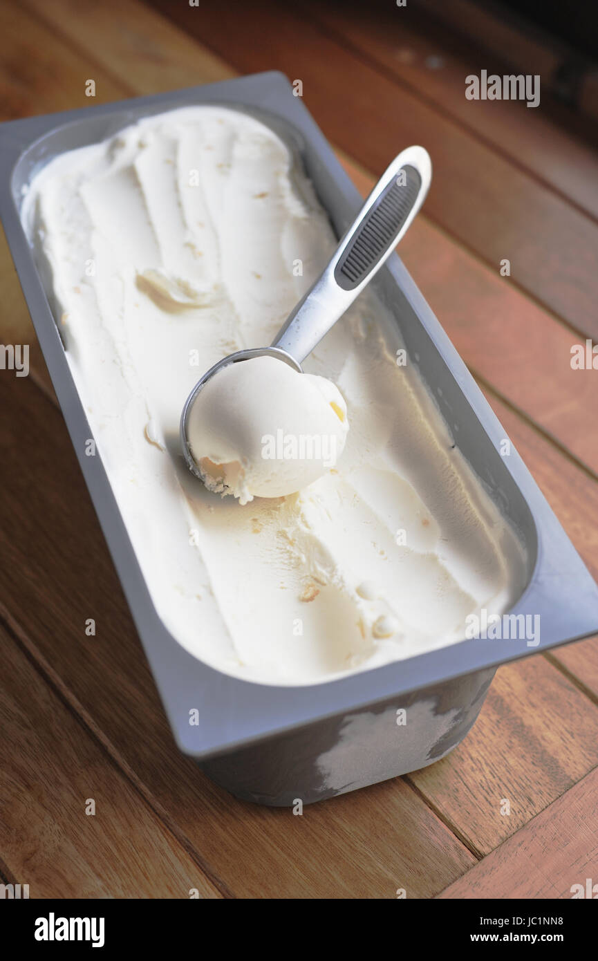 Glace vanille bio faits maison scoop, creusées dans un contenant de Banque D'Images