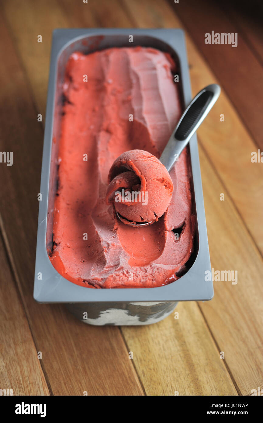 Fraise Bio faits maison cuillère à crème glacée de fruits, creusées dans un contenant de Banque D'Images Fraise Bio faits maison cuillère à crème glacée de fruits, creusées dans un contenant de Banque D'Images