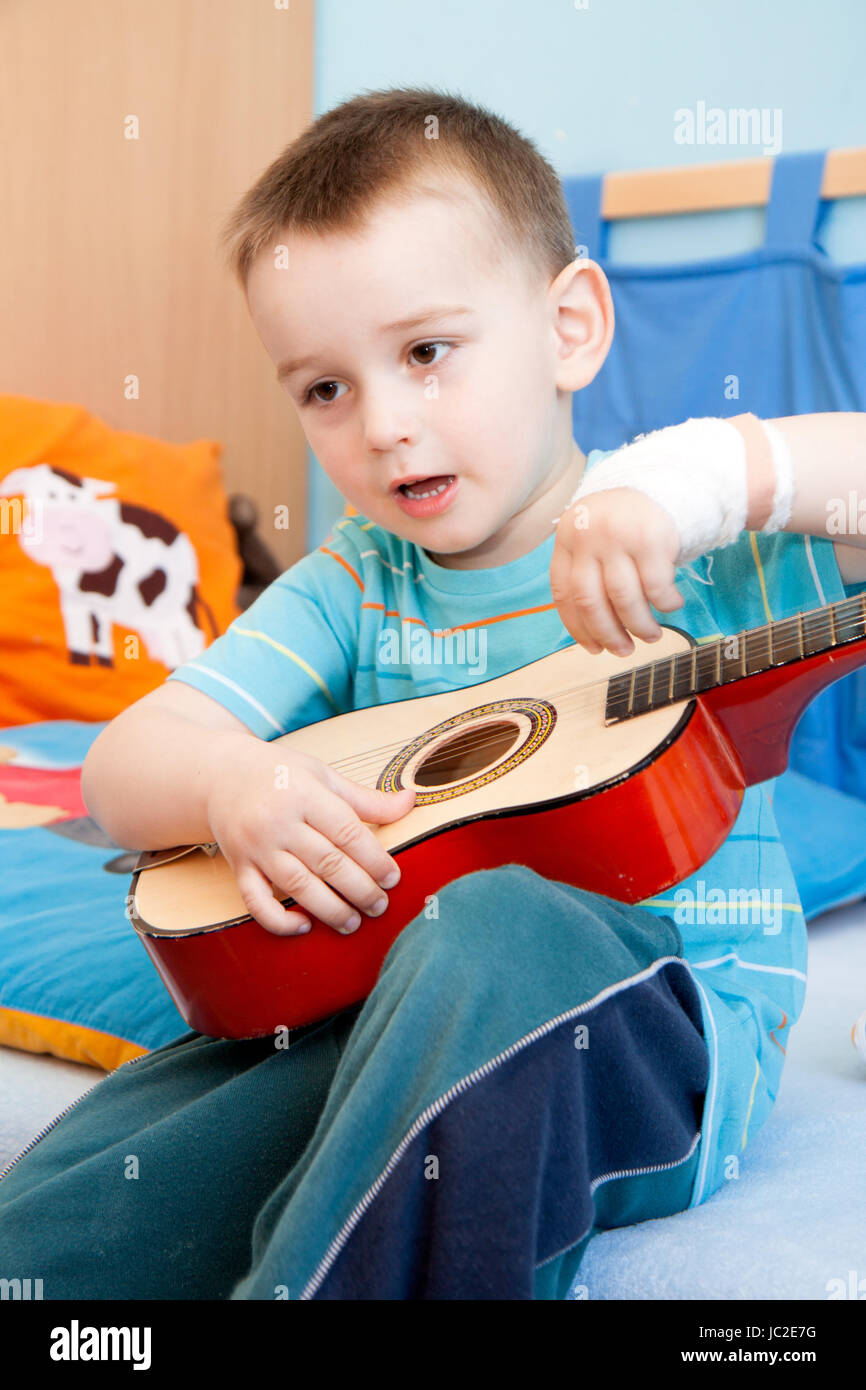 Blessé à la main gauche avec bandage garçon à tourné en home avec guitare Banque D'Images