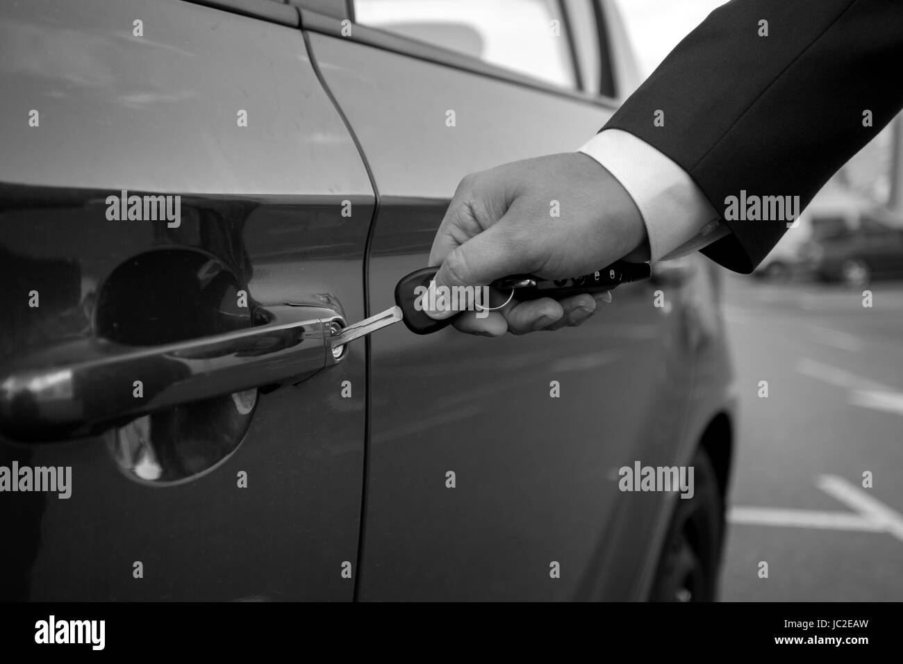 Noir et blanc photo gros plan de l'insertion de l'homme dans le trou de clé de voiture Banque D'Images