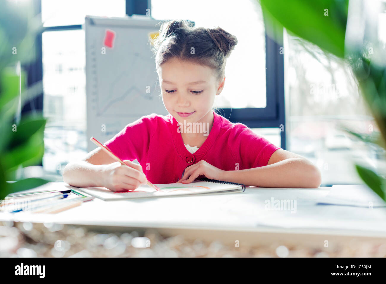 Smiling little girl sitting at desk in office et de dessin Banque D'Images