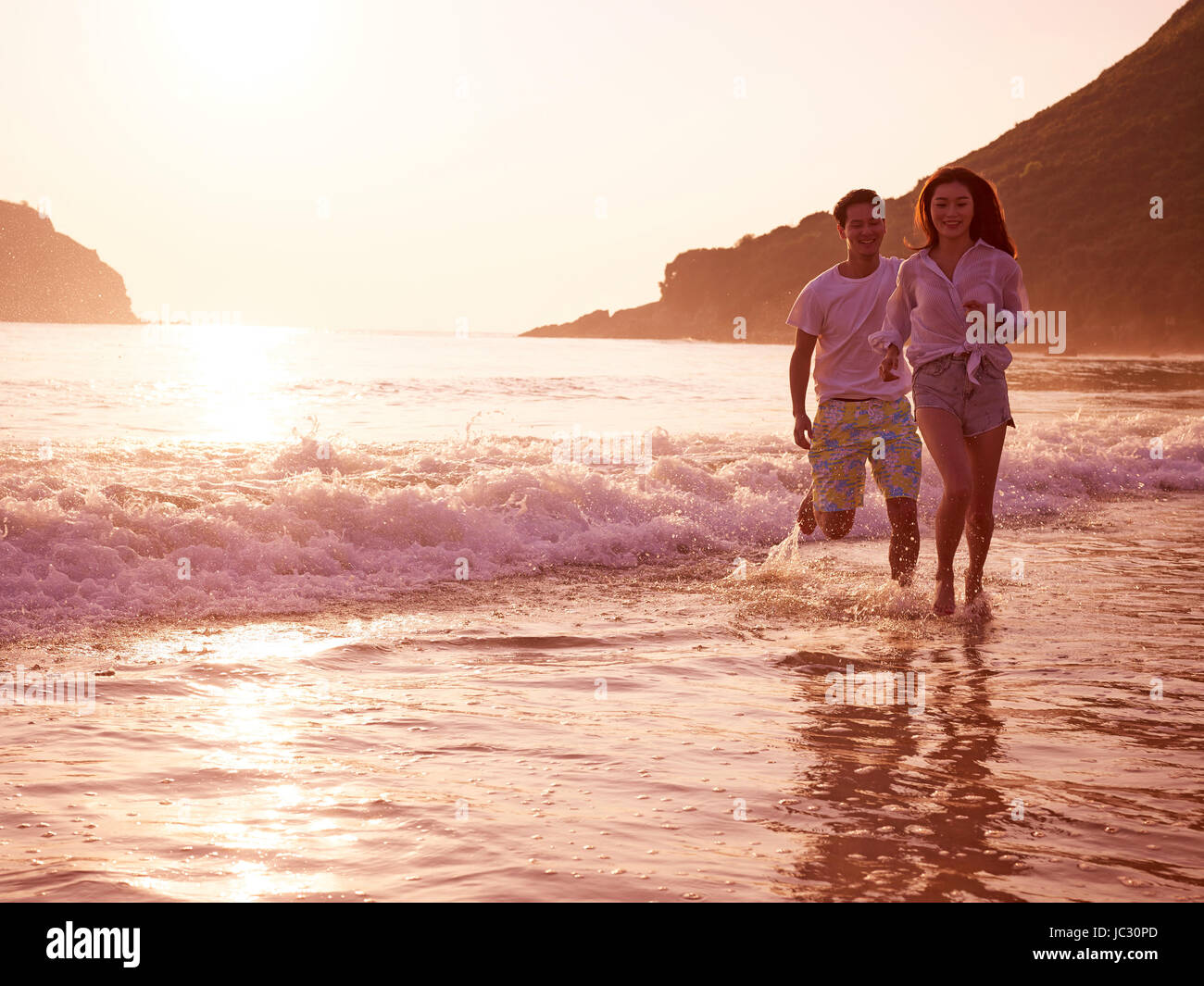 Happy young asian woman on beach in pendant le coucher du soleil ou le lever du soleil. Banque D'Images