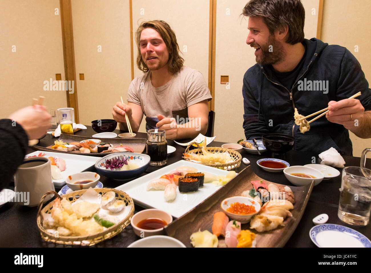 Un homme européen faisant face au wasabi en mangeant des sushis à Harbour Town Otaru, Hokkaido au Japon tandis que ses amis rire. Banque D'Images