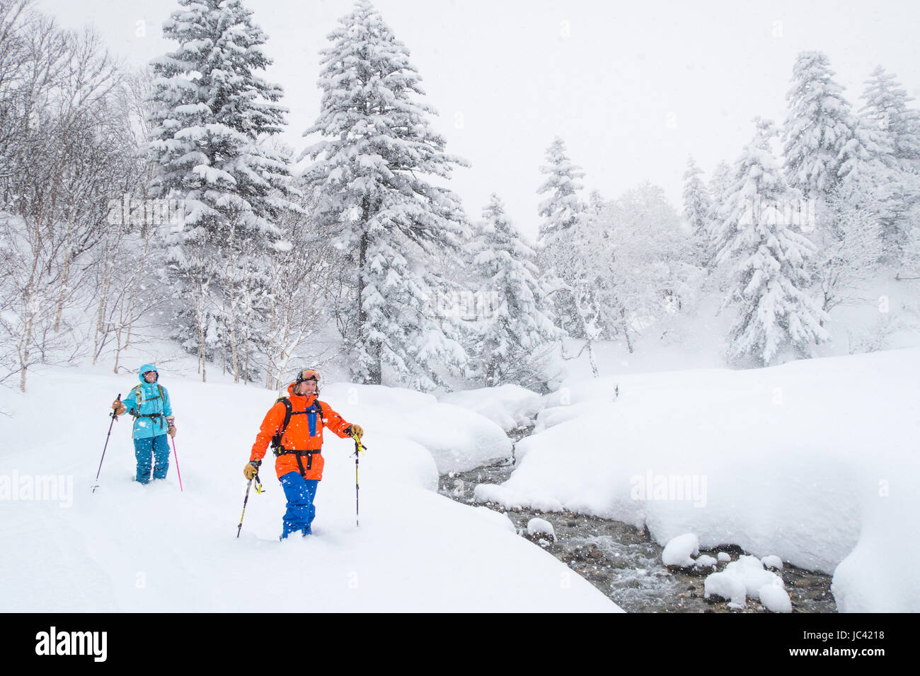 Deux skieurs de l'arrière-pays (un homme et une femme en vêtements colorés) sont le ski de randonnée à l'Tokachidake, une montagne à Kamifurano sur Hokkaido, Japon. Banque D'Images
